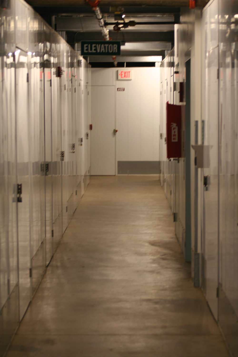 A hallway with many doors and a red sign.