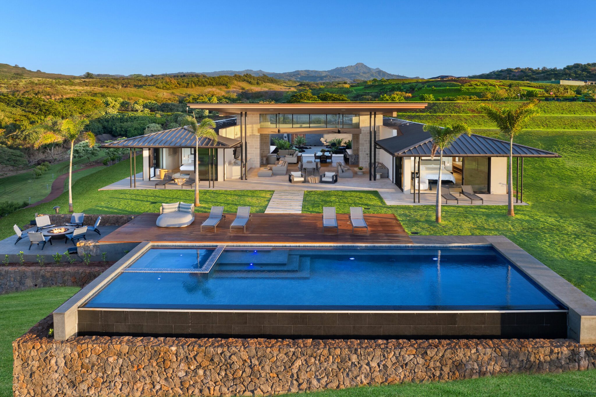 A large pool in front of a house with a lot of grass.