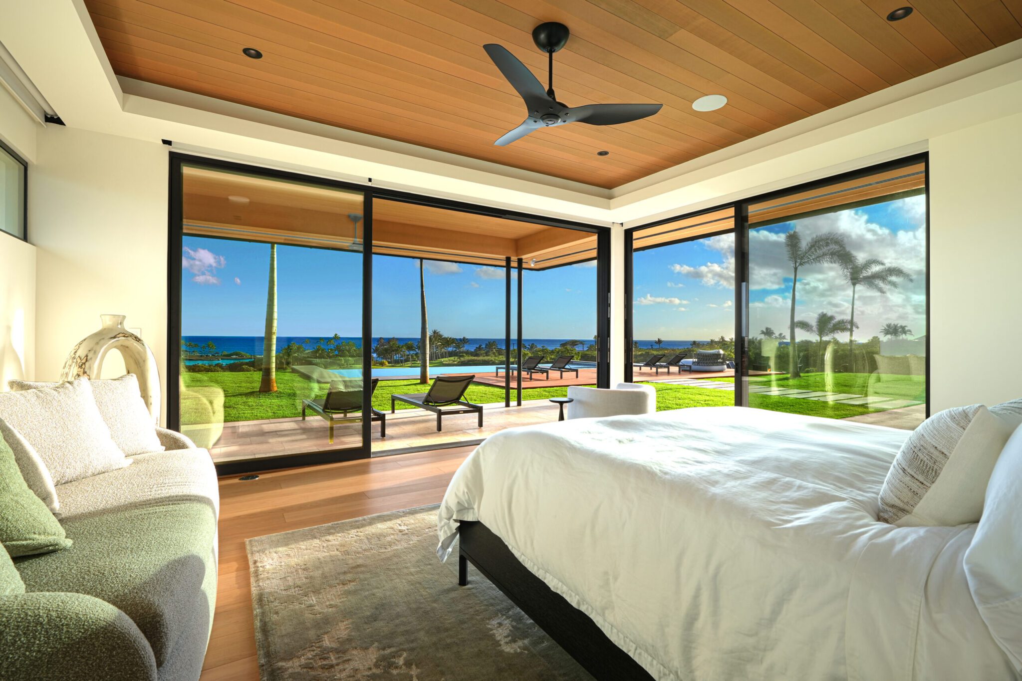 A bedroom with large windows and a view of the ocean.