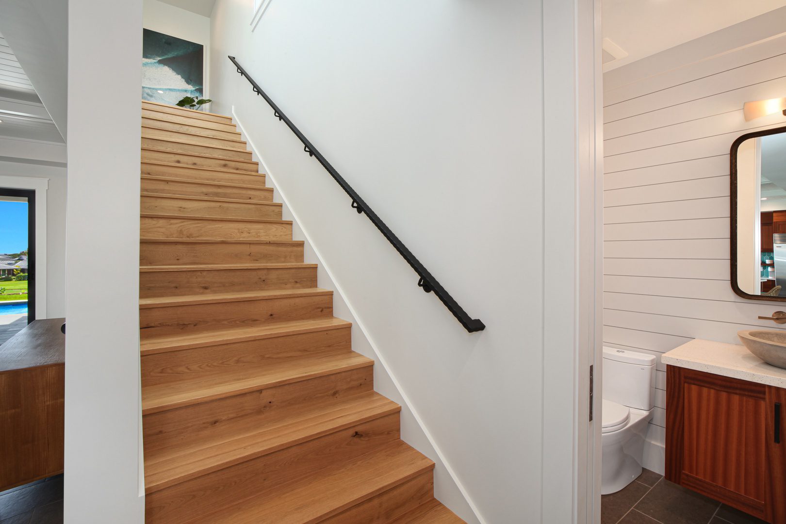 A wooden staircase with black handrails and white walls.