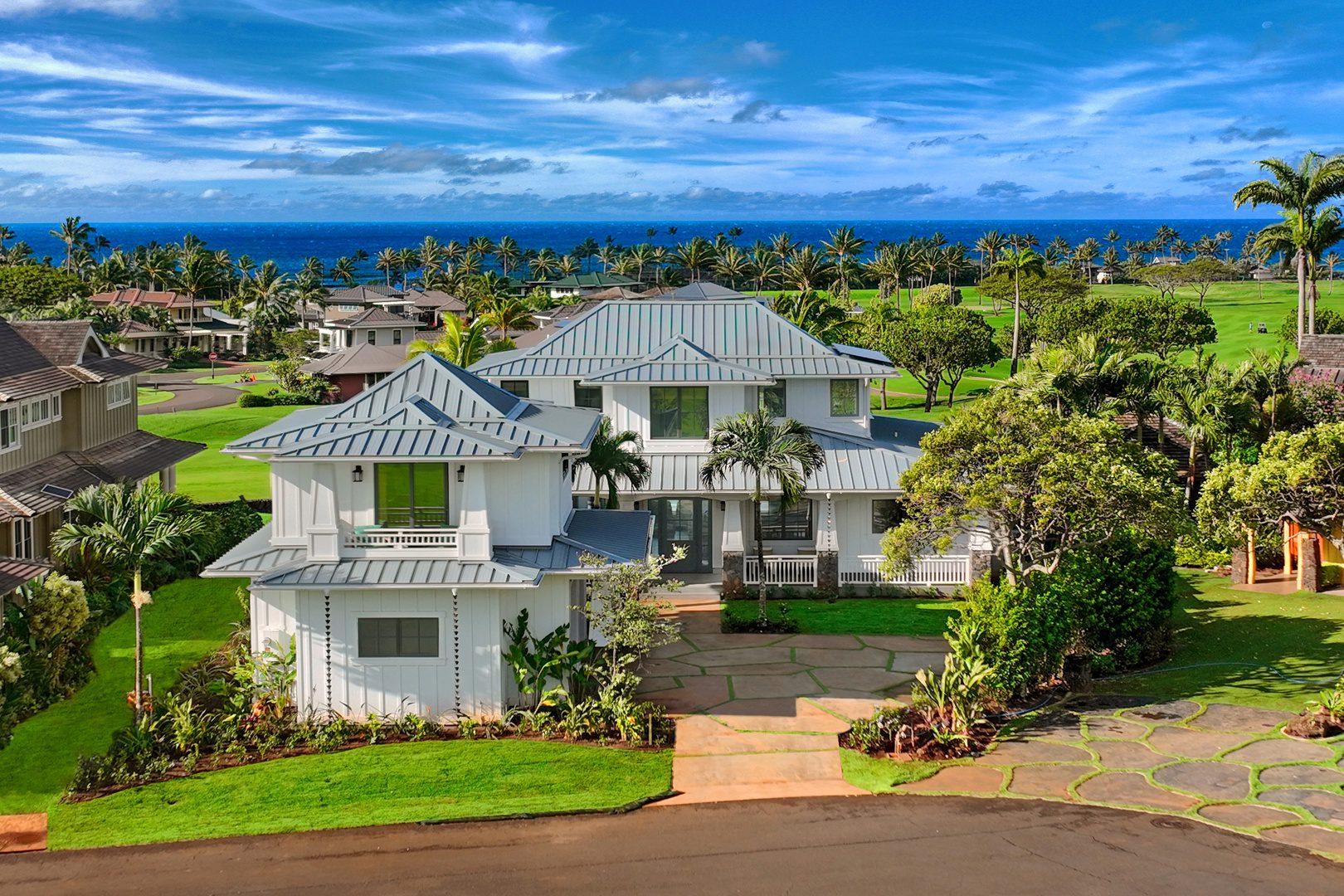 A large white house with green shutters and a driveway.