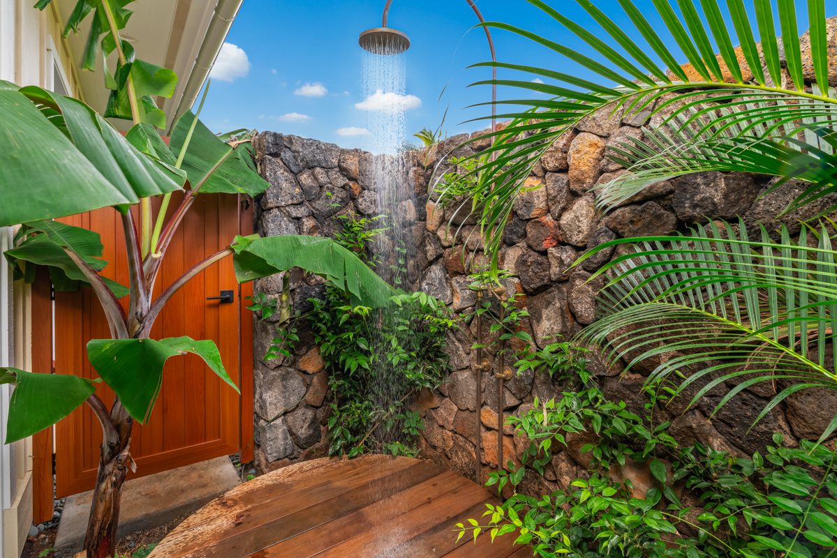 A shower with plants and rocks in the background.