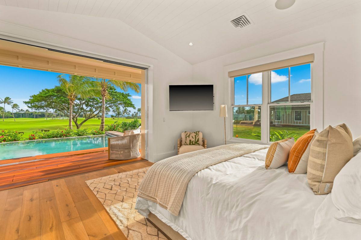 A bedroom with a view of the pool and trees.