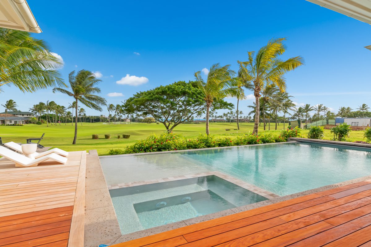 A pool with an outdoor deck and palm trees.