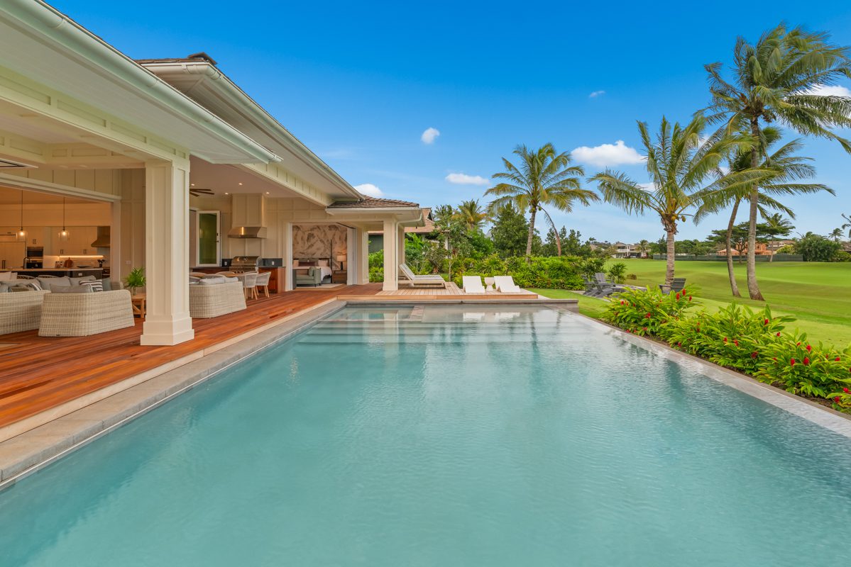 A pool with an open air deck and lawn.