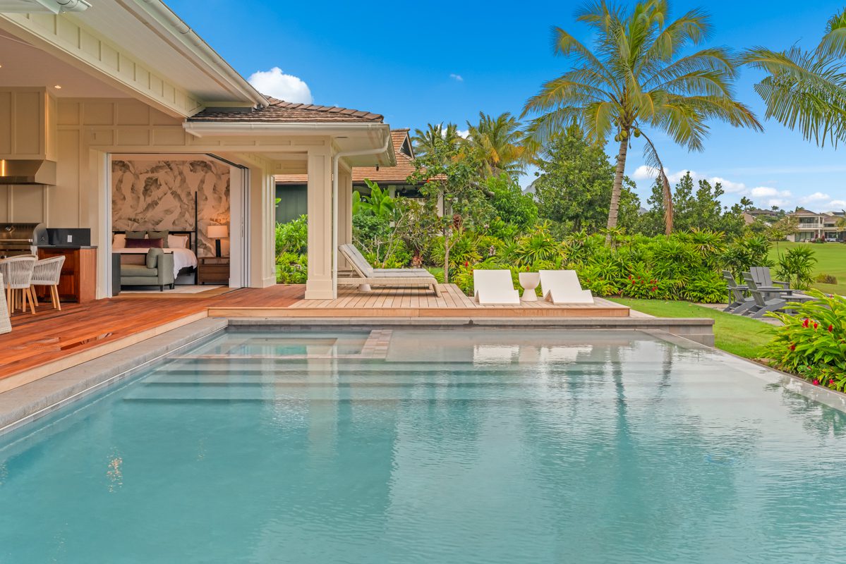 A pool with chairs and a house in the background
