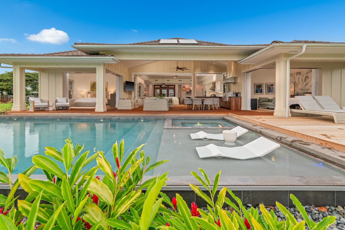 A large pool with chairs and a house in the background.