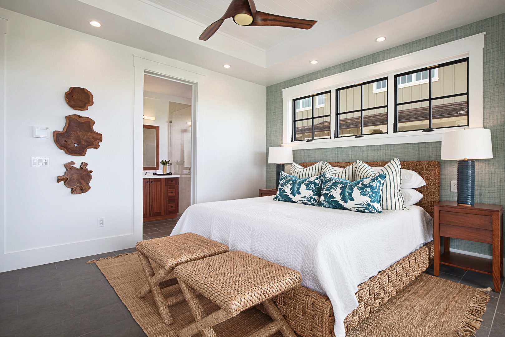 A bedroom with a bed, two stools and a window.