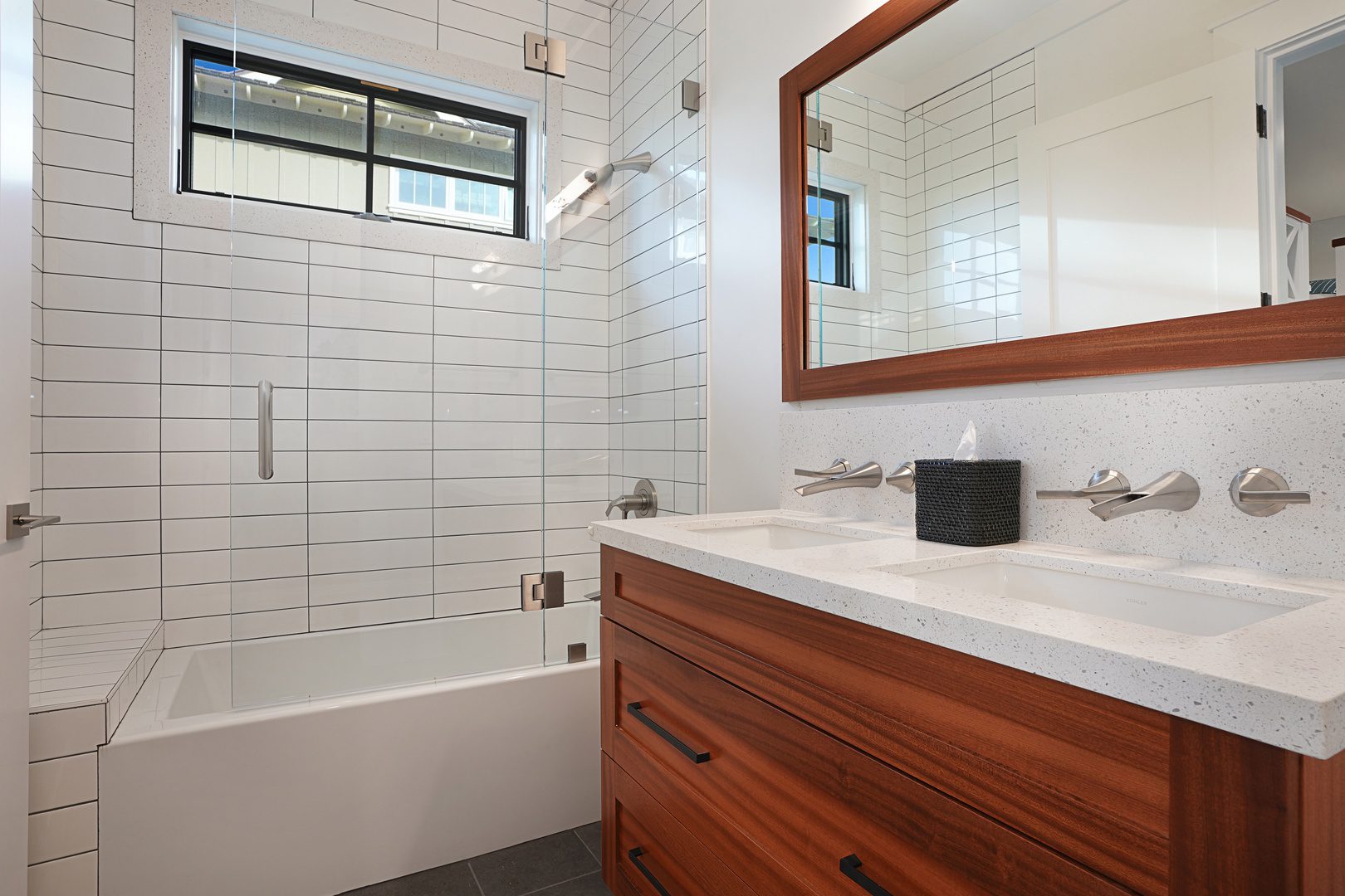 A bathroom with a sink, mirror and bathtub.