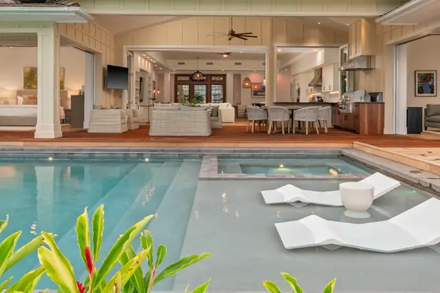 A pool with two chairs and a table in the middle of it.